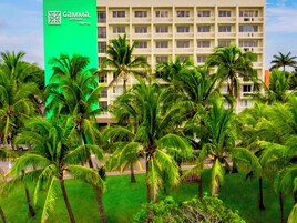 Un edificio de hotel con un letrero verde, rodeado de palmeras.