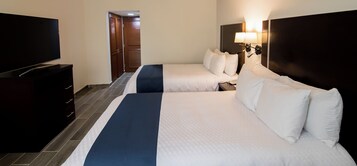 Quarto de hotel com duas camas, uma televisão, uma cômoda e uma porta que dá para outro espaço.