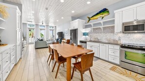 A modern kitchen with white cabinetry, a wooden dining table, and a fish decoration on the wall. - Come stay with us at the Golden Hour! Spacious and relaxing 2 bed/2 bath cond (Port Aransas)