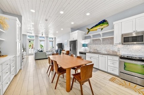 A modern kitchen with white cabinetry, a wooden dining table, and a fish decoration on the wall.