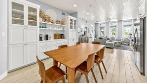 A modern kitchen with white cabinetry, a wooden dining table, and a living area with a sofa and coffee table. - Come stay with us at the Golden Hour! Spacious and relaxing 2 bed/2 bath cond (Port Aransas)