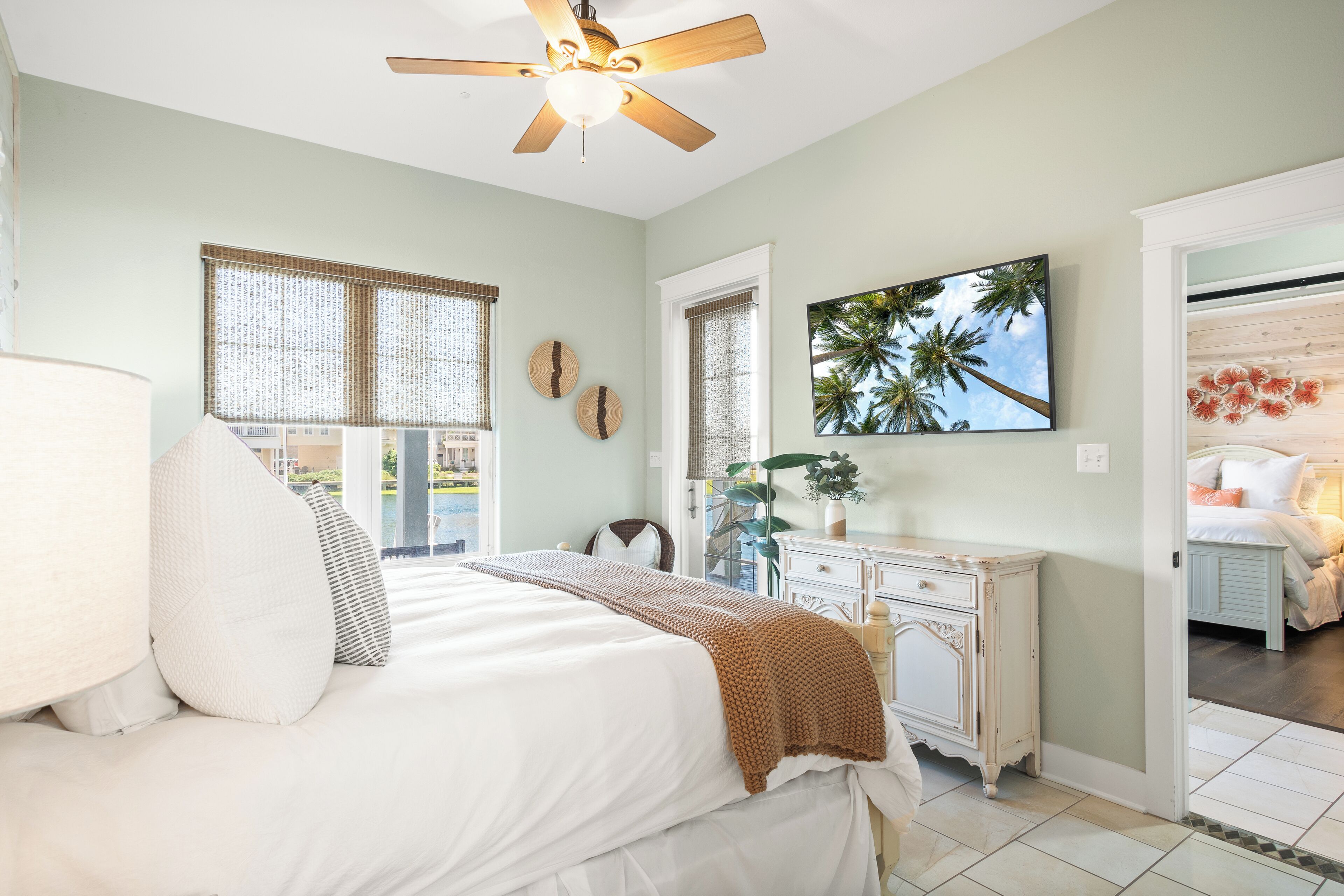 A bedroom with a bed, a ceiling fan, a dresser, and a window with blinds.