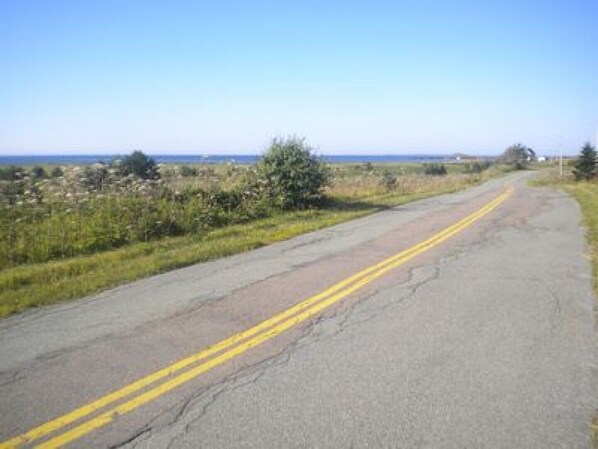 A rural road with double yellow lines, surrounded by fields and a clear sky.