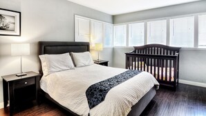 A bedroom with a large bed, two bedside tables, a nightstand, a crib, and a framed picture on the wall. - **Water Slide!**Pool**Spa**Game Room!! (Anaheim)