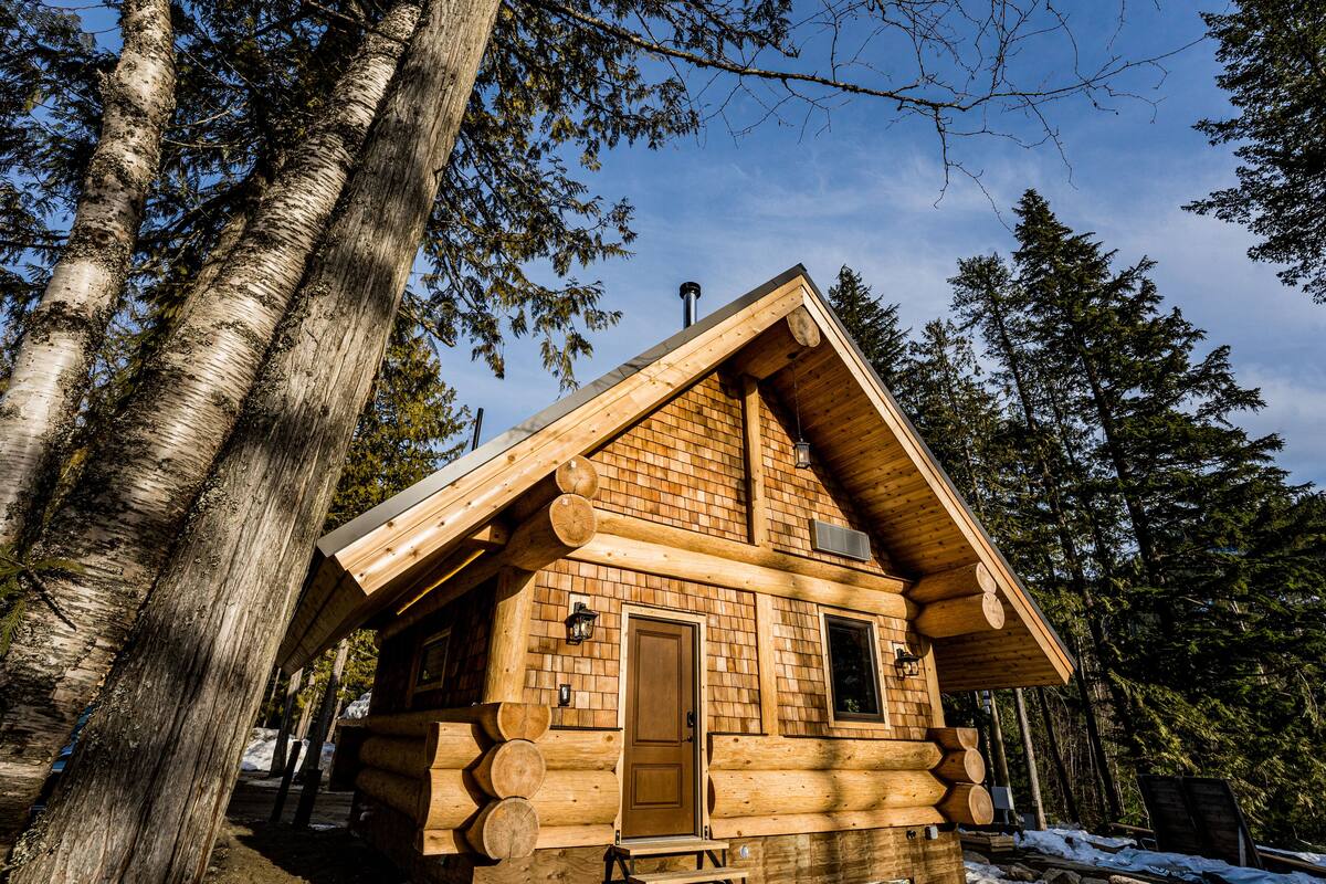 A log cabin with a wooden exterior, a pitched roof, and a door.