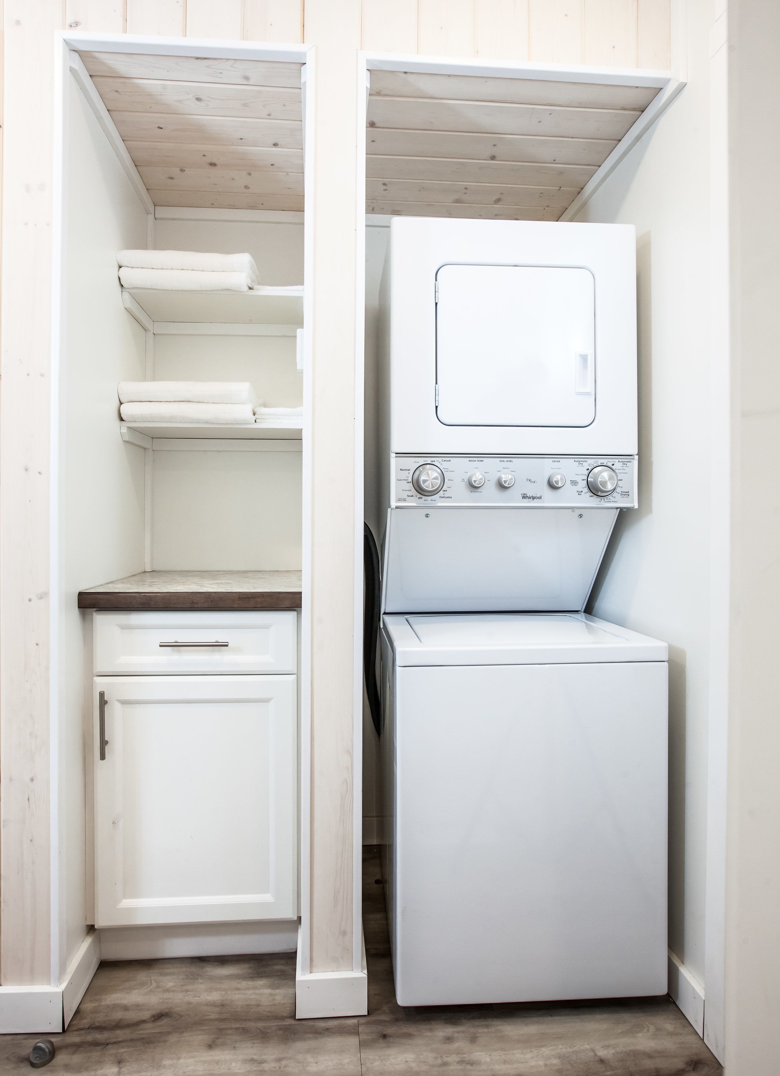 A laundry room with a washing machine and dryer, wooden cabinets, and a small countertop.