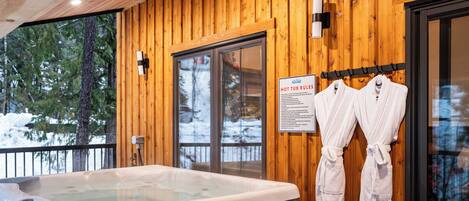 A wooden cabin with a hot tub, wooden walls, and a sign with hot tub rules.