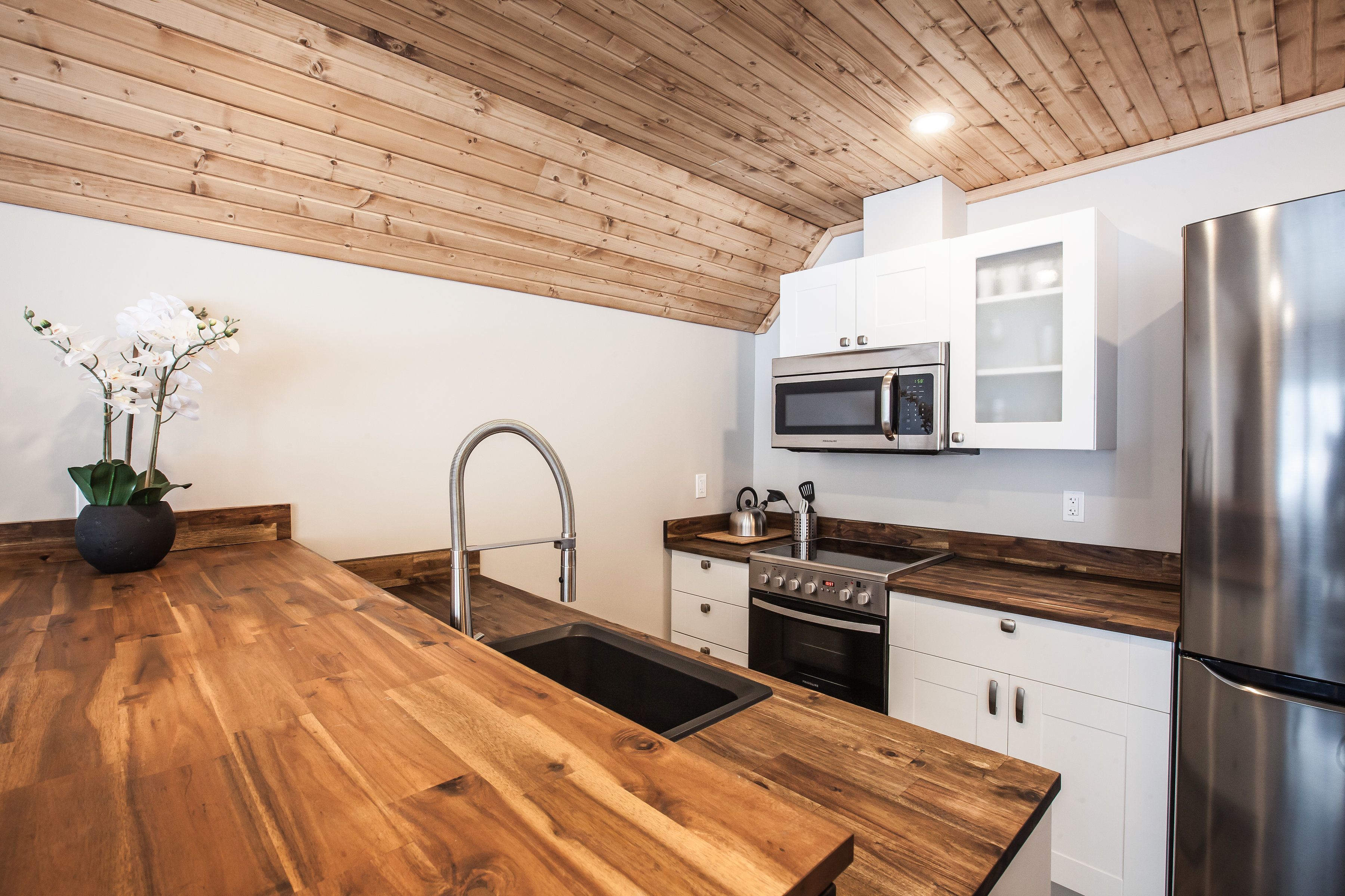 Una cocina moderna con encimeras de madera, electrodomésticos de acero inoxidable y armarios blancos.