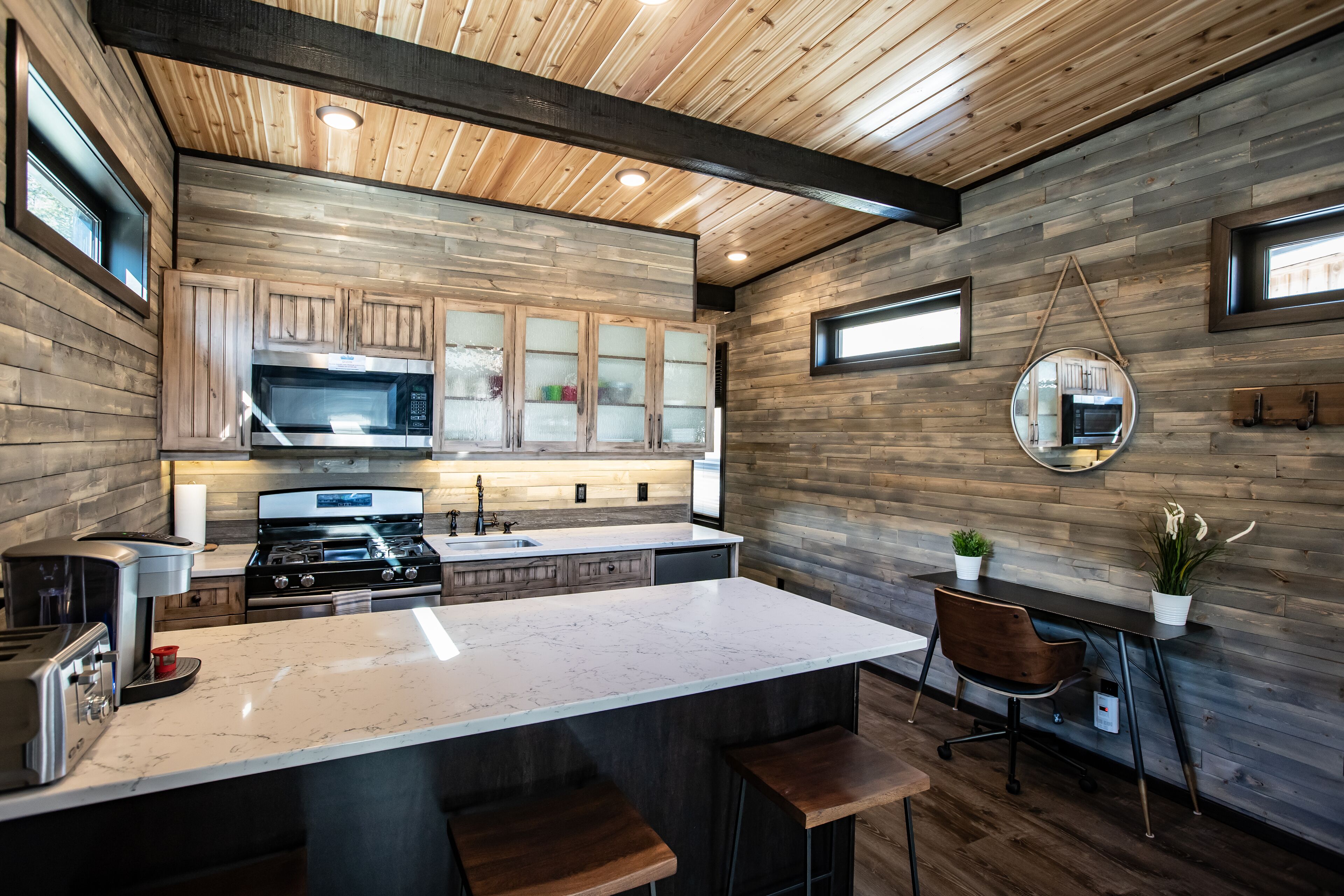 A modern kitchen with wooden walls, a marble countertop, and a central island with bar stools.