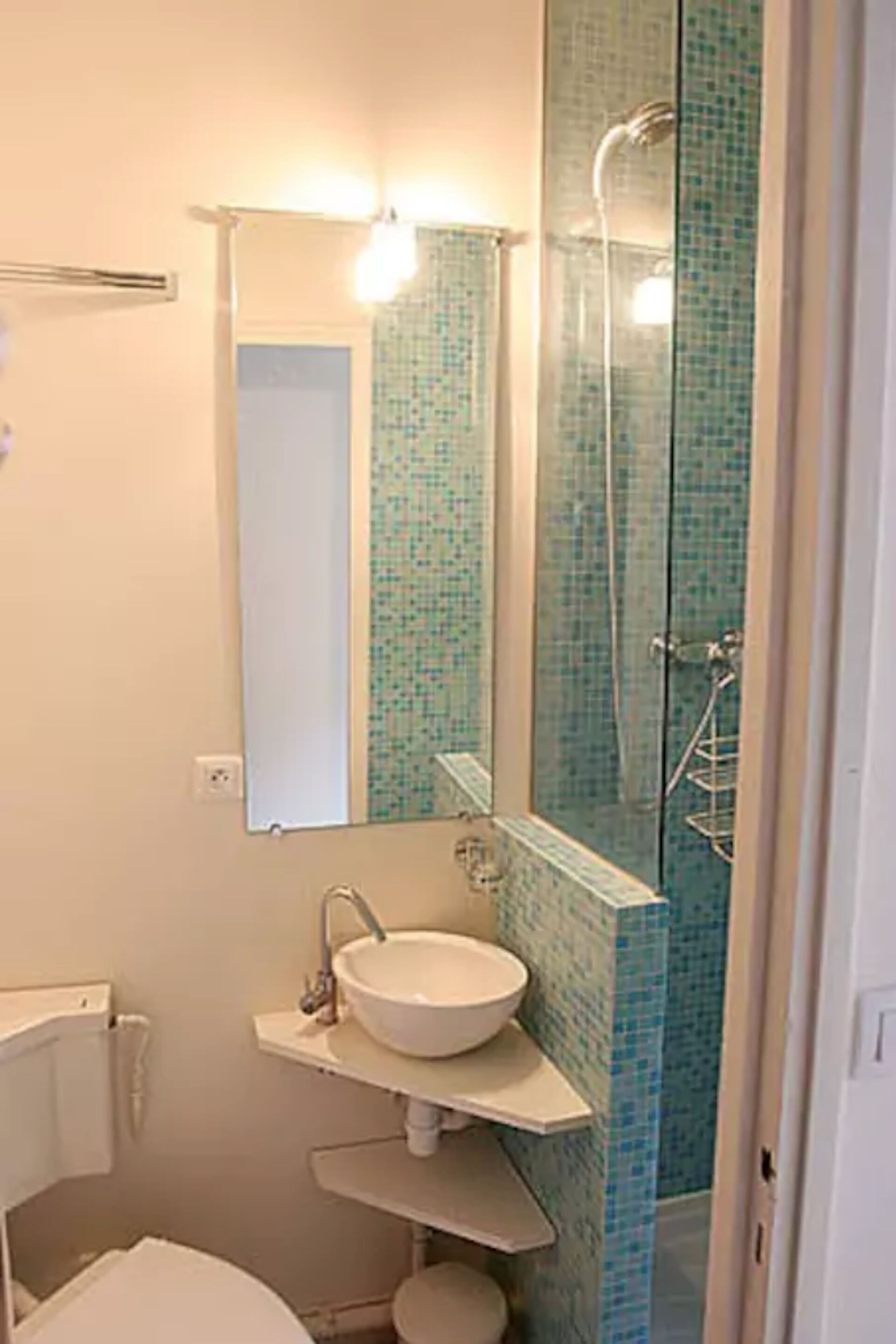 A bathroom with a white sink, a mirror, and a shower with blue mosaic tiles.