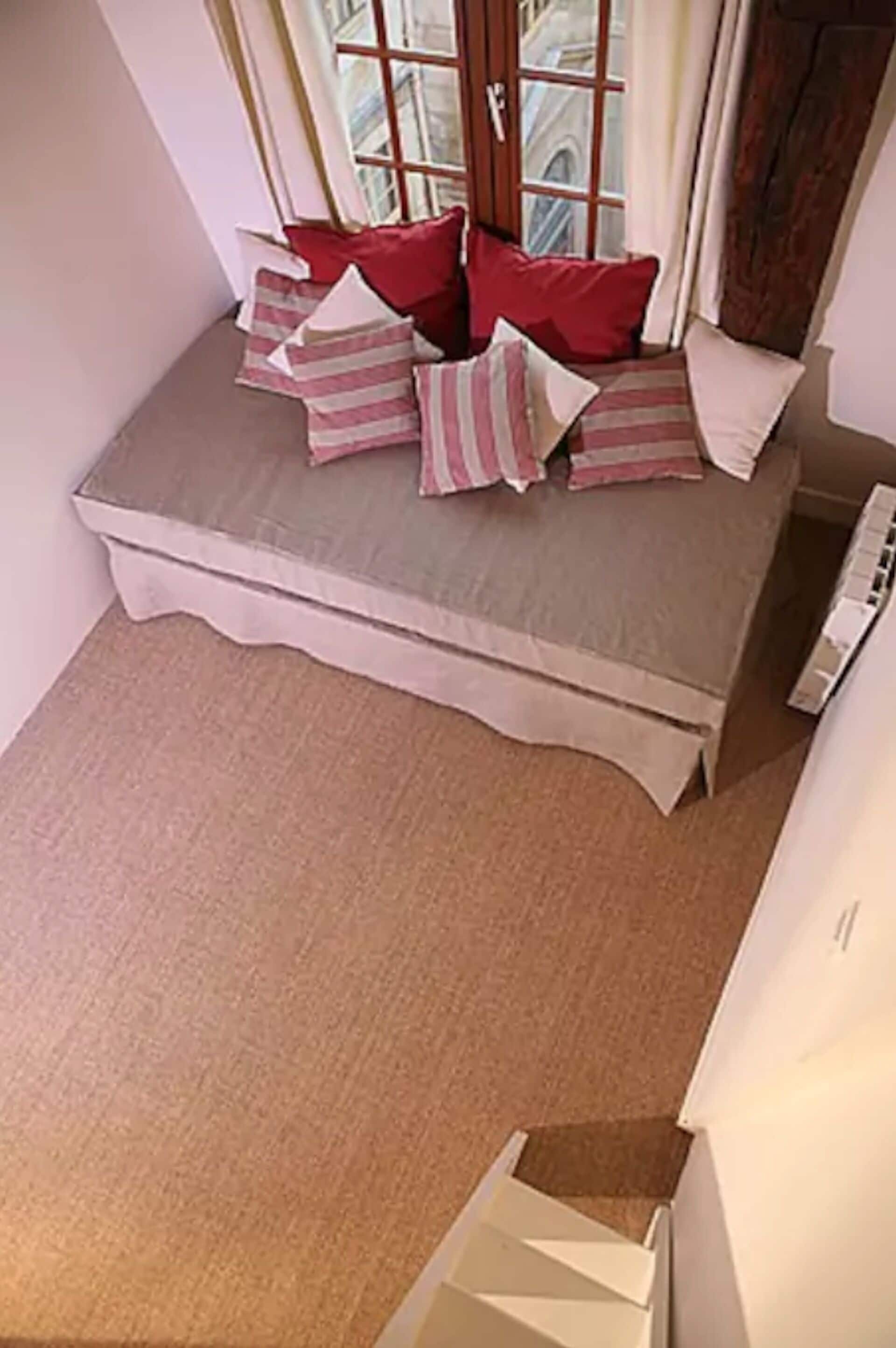 A corner bedroom with a built-in bench and a window.