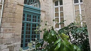 A historic building with a central arched entrance and multiple windows. - Charming cozy triplex in trendy Marais (Paris)