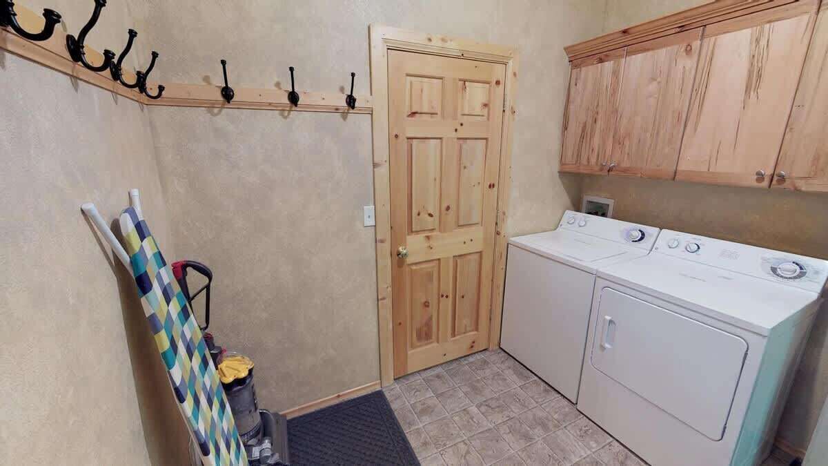 A laundry room with a washing machine, a wooden door, and a coat rack with a checkered item hanging.