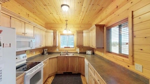 A kitchen with wooden cabinets, a microwave, a stove, and a sink. - 31 MI to YNP | Fire Pit | Sleeps 10 (Island Park)