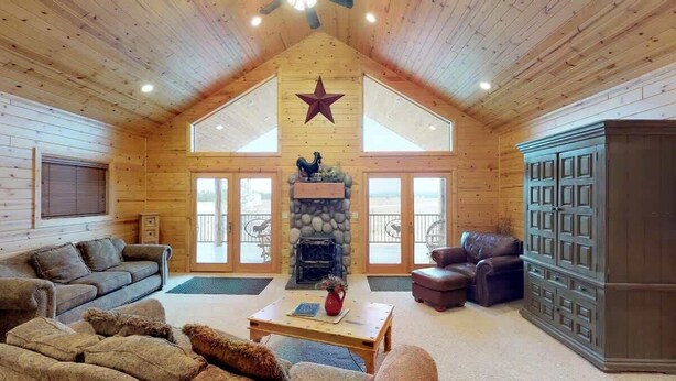 A log cabin interior with a stone fireplace, leather furniture, and a star on the ceiling. - 31 MI to YNP | Fire Pit | Sleeps 10 (Island Park)