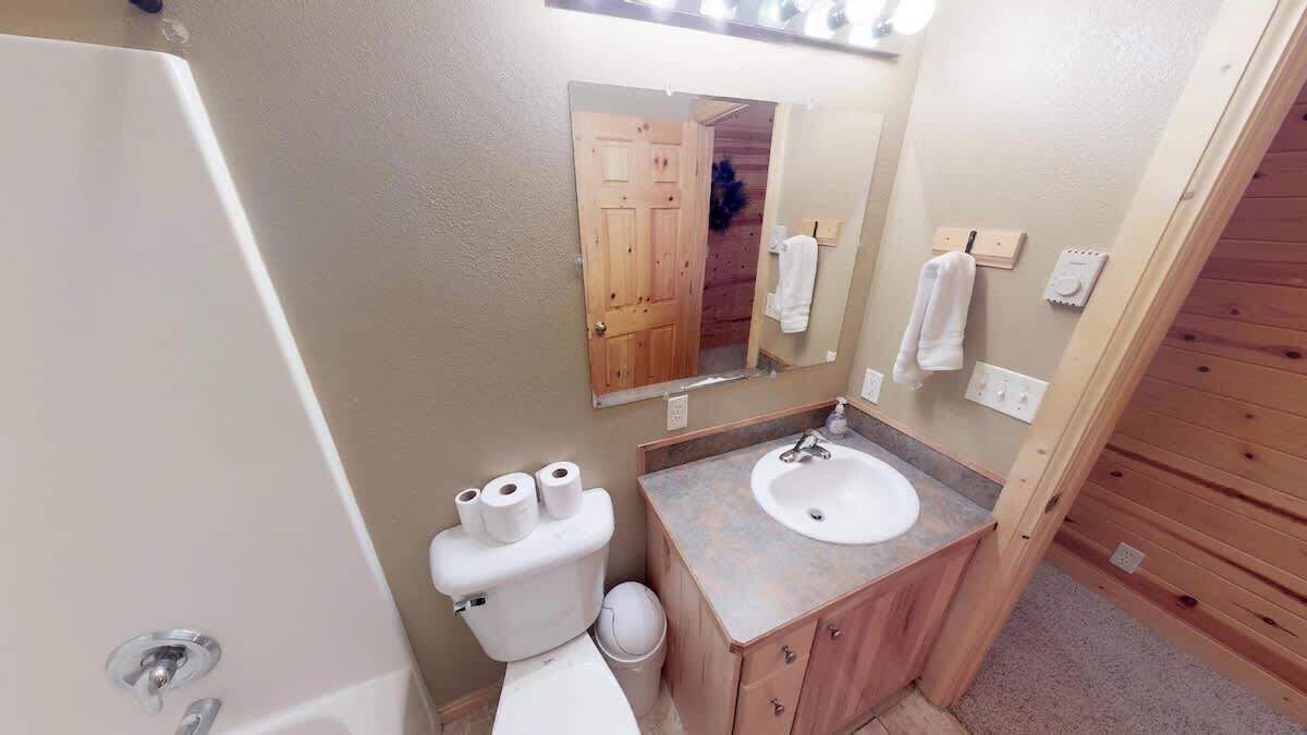 Ein Badezimmer mit Toilette, Waschbecken, Spiegel und Holzwänden.