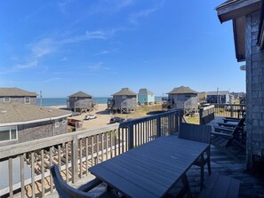Una terraza de madera frente a la playa, con vistas al océano y a las casas de la costa.