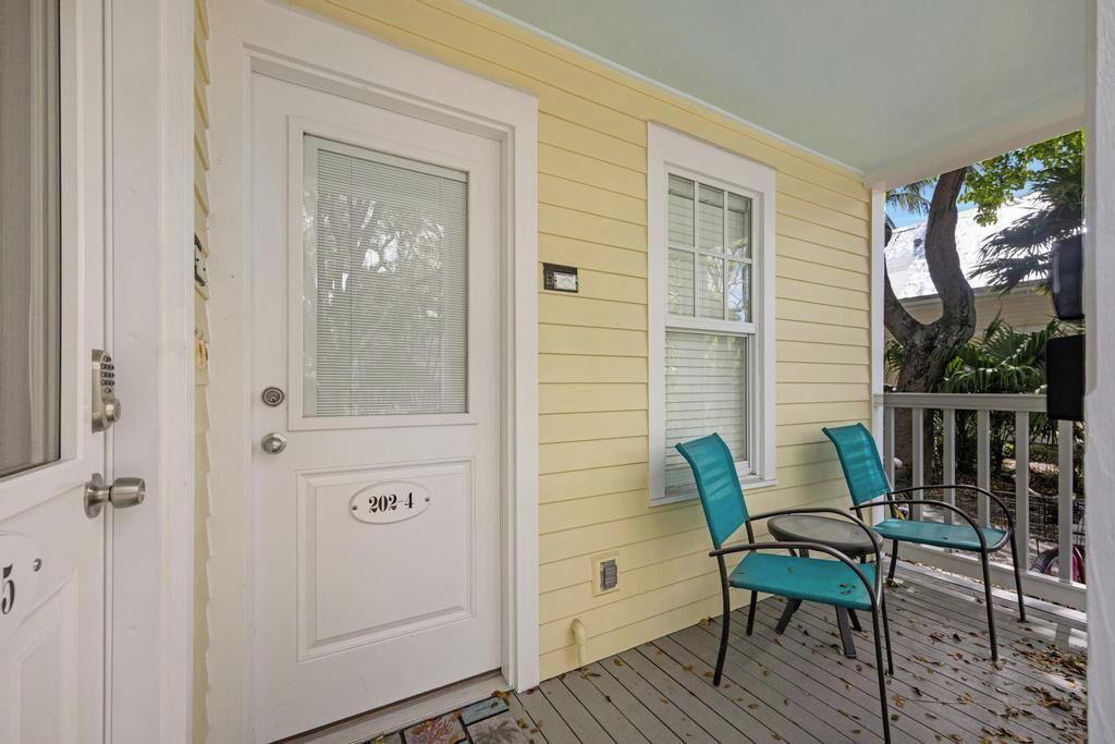 A porch with a white door marked "202-4" and two teal chairs.