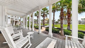 A covered outdoor area with white wooden chairs and tables, palm trees, and a view of a residential area. - Breathtaking Home in Cinnamon Shore w/ Access to Resort-Style Amenities (Port Aransas)