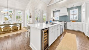 A spacious kitchen with white cabinetry, a large island, and a view of the outdoors. - Breathtaking Home in Cinnamon Shore w/ Access to Resort-Style Amenities (Port Aransas)