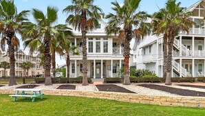 A coastal hotel with a white facade, multiple balconies, and palm trees. - Breathtaking Home in Cinnamon Shore w/ Access to Resort-Style Amenities (Port Aransas)