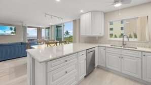 A modern kitchen with white cabinetry, a granite countertop, and a built-in dishwasher.