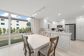 Une cuisine moderne avec des meubles blancs, des appareils en acier inoxydable et une grande table à manger.