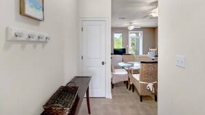 A hallway with a white door, a wicker bench, wicker chairs, a small table, and a ceiling fan. - ☀️Community Pool-PRIME 30A Location-Topsail Village 422☀️ (Santa Rosa Beach)