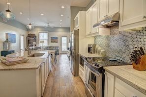 A spacious kitchen with a central island, stainless steel appliances, and a tiled backsplash.