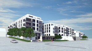 A modern multi-story building with balconies, a covered entrance, and a landscaped area with trees. - New apartment "Säntis", 70 m² (Friedrichshafen)