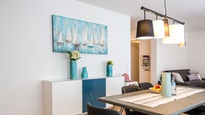 A modern dining area with a table, chairs, and a blue abstract painting on the wall. - New apartment "Säntis", 70 m² (Friedrichshafen)