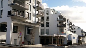 A modern multi-story residential building with balconies, a covered entrance, and a no parking sign. - New apartment "Säntis", 70 m² (Friedrichshafen)