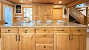 Une cuisine avec des armoires en bois, un plan de travail en granit et un plafond en bois.