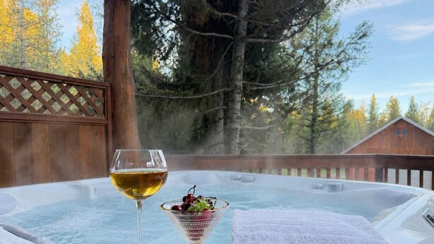 Un bain à remous, un verre de vin blanc et un bol de cerises, le tout posé sur un plateau en bois.