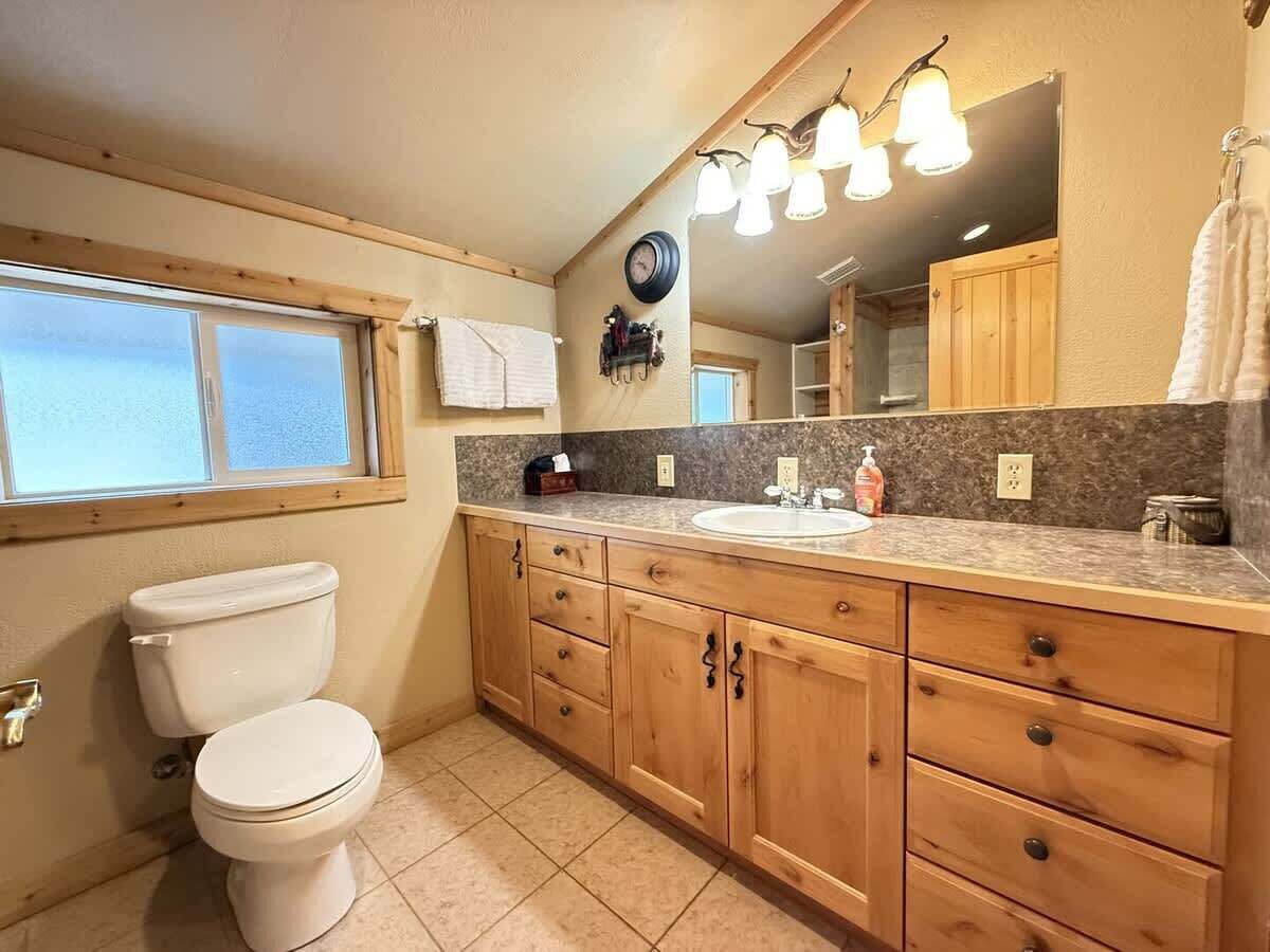 Ein Badezimmer mit Toilette, Holzschränken, einem Waschbecken und einem Spiegel.