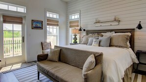A bedroom with a large bed, a sofa, and a window with blinds.