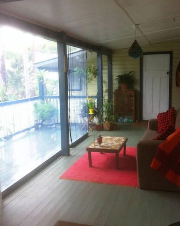 Una habitación con alfombra roja, una mesa de madera, un sofá y una planta en maceta.