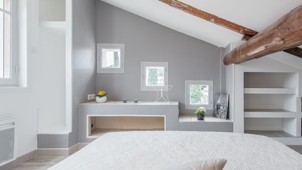 Une chambre moderne avec un grand lit, un bureau intégré et une fenêtre donnant sur un espace verdoyant.