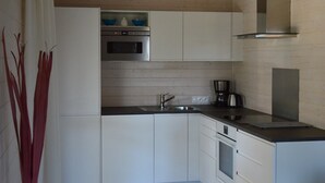 A modern kitchen with white cabinets, stainless steel appliances, and a black countertop.
