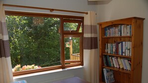 A room with a large window, a wooden bookshelf, and a desk with a printer.