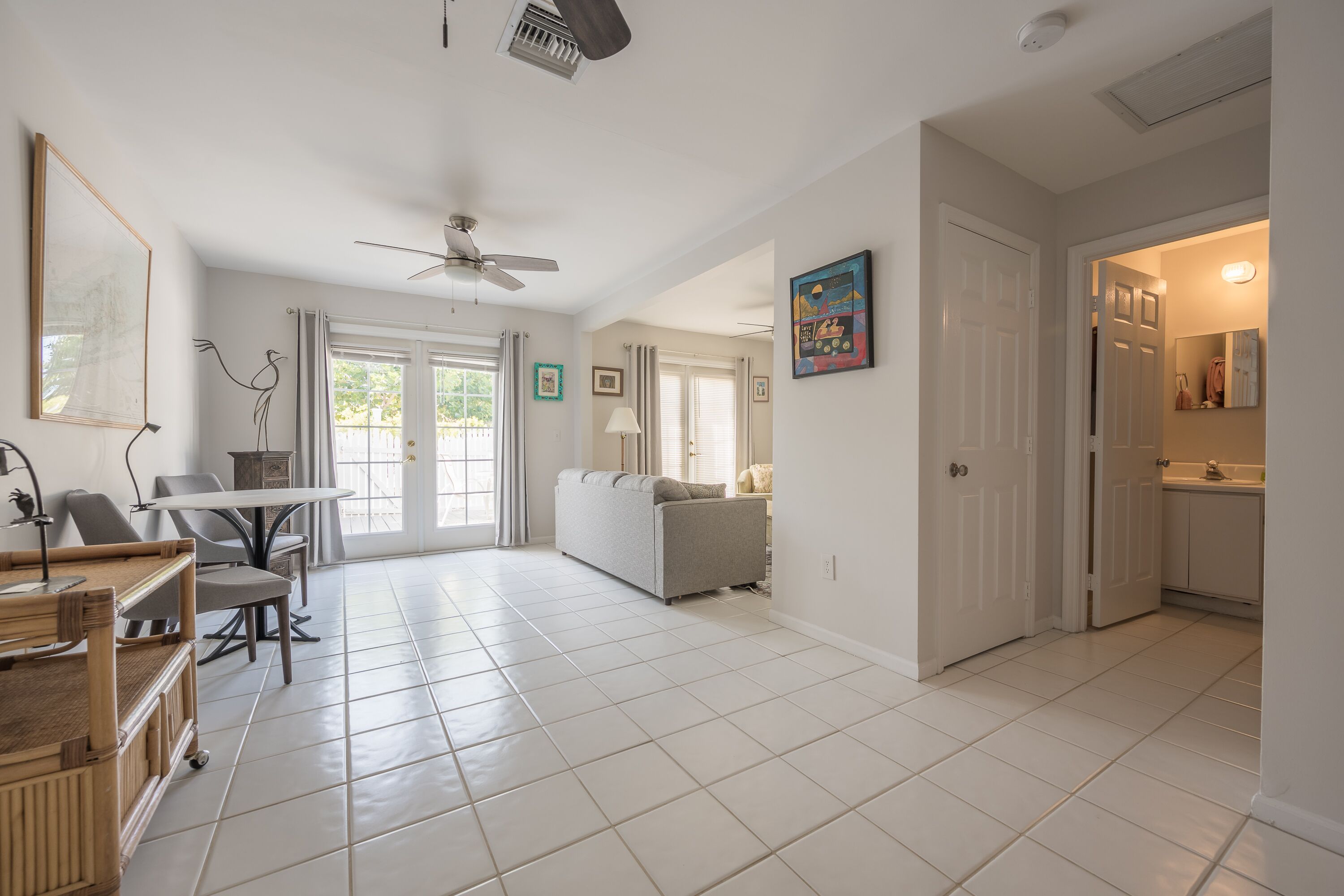 A spacious living area with a dining table, sofa, and a ceiling fan.