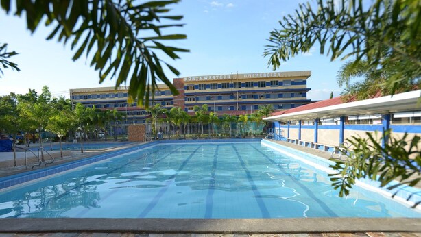 Ein Schwimmbecken mit klarem Wasser, umrahmt von Steinfliessen, mit einem Gebäude im Hintergrund, auf dem 'Northwestern University' steht.