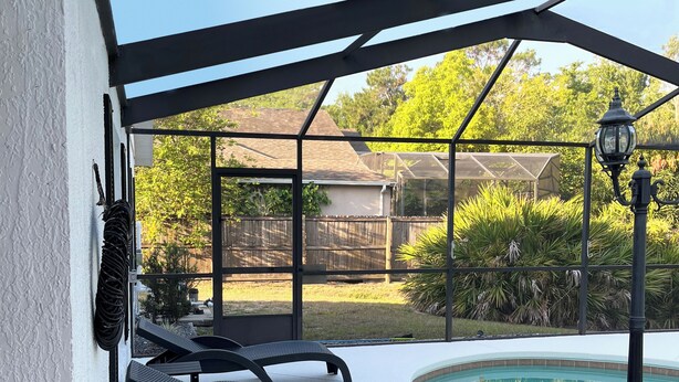 Ein überdachter Außenbereich mit Pool, Liegestühlen und einer Pergola.