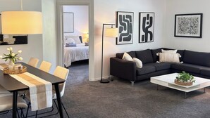 Ein modernes Wohnzimmer mit Essbereich, einem schwarzen Sofa und einem weißen Couchtisch.