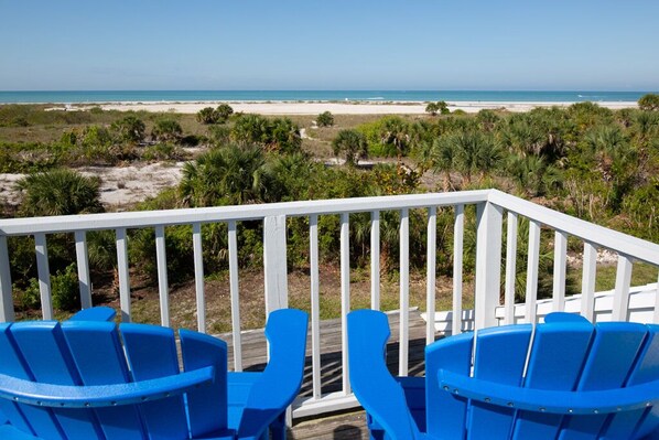 Une terrasse avec des chaises bleues donnant sur une plage.