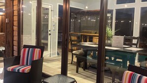 An outdoor patio area with wicker furniture and a glass door leading to an indoor space. - Spacious 4BR Retreat with Pool and Spa (Rowlett)