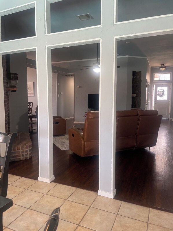 A spacious living area with a brown leather sofa, a television, and a stone fireplace. - Spacious 4BR Retreat with Pool and Spa (Rowlett)