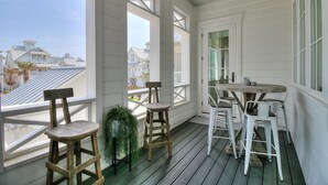 Un portico riparato con sedie e tavolo in legno, ampie finestre e vista sulle case.