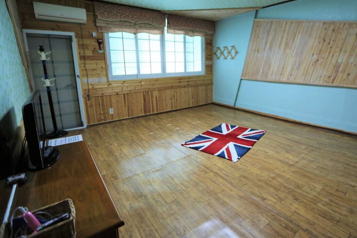 Ein Zimmer mit Holzboden, einem Vorhangfenster, einer Holzpaneelausstattung und einem Teppich mit Union Jack Design.