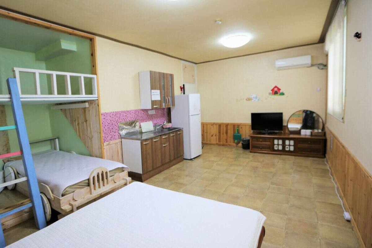 Ein kleines Zimmer mit Etagenbetten, einer Küchenzeile, einem Fernseher und einem kleinen Tisch.